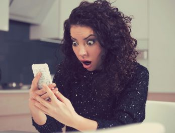 woman viewing her smartphone and looking surprised
