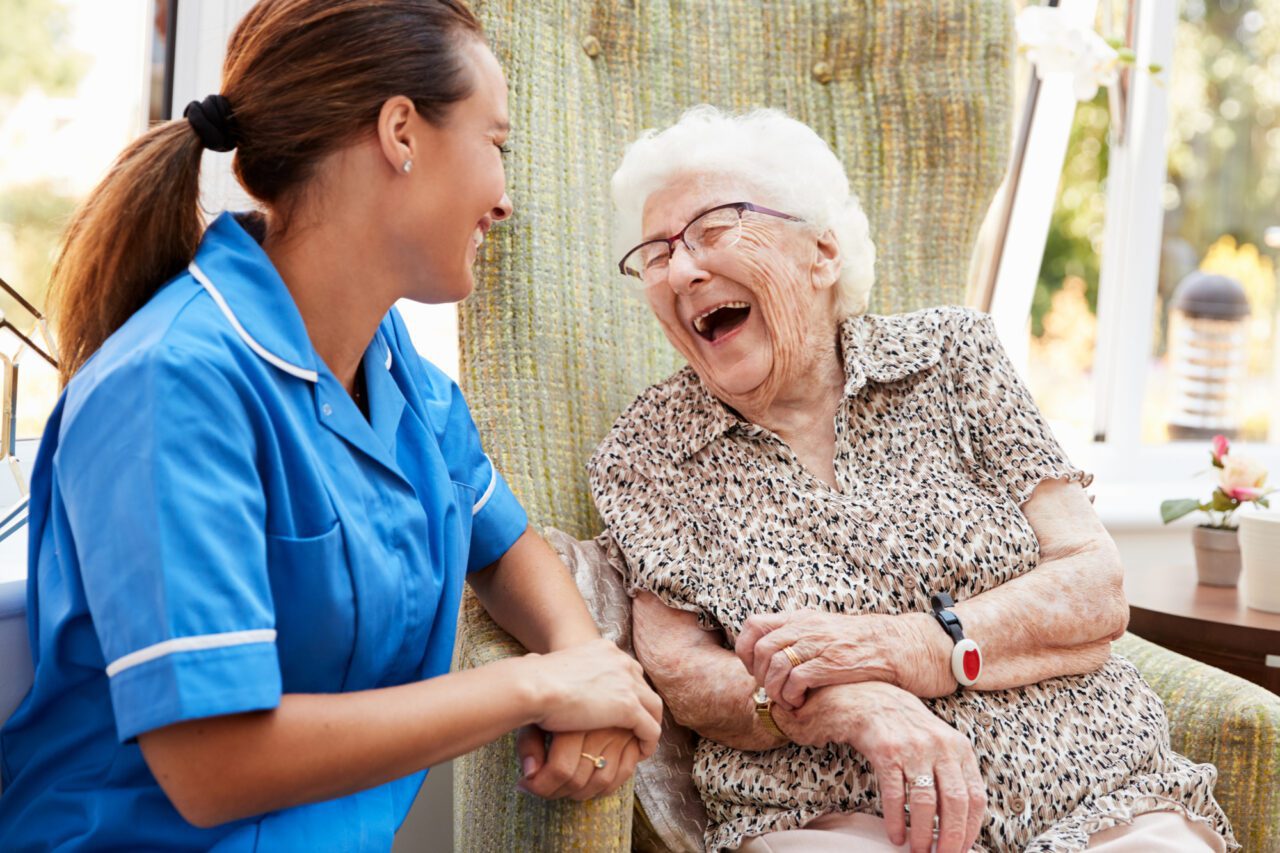 elderly woman laughing with her caretaker