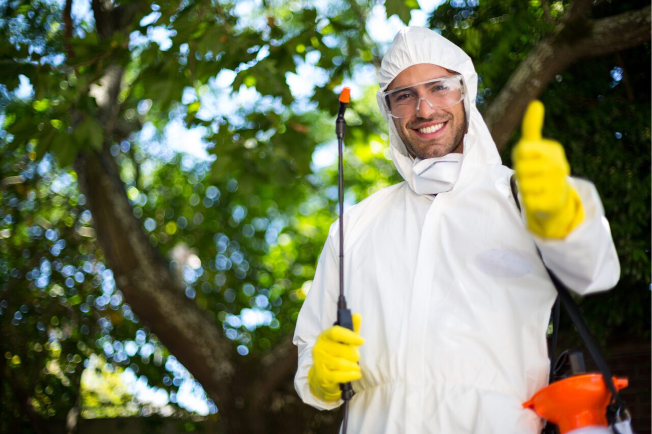 man in white protective gear doing outdoor chemical treatments