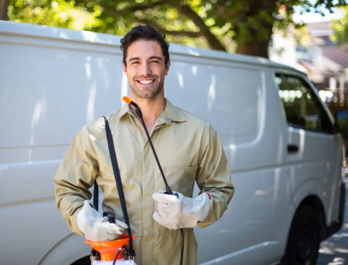 Pest control worker smiling next to a white van.