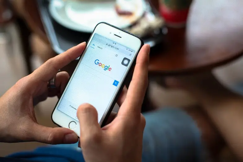 Person typing into a Google search bar on their smartphone.